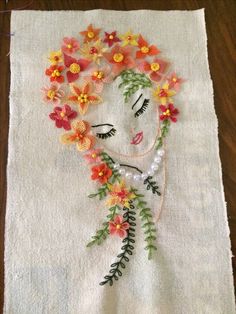 a piece of art made out of flowers on a white towel with pearls and beads