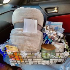 a basket filled with towels and other items in the back seat of a car,