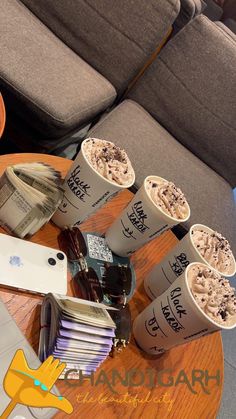 two cups of ice cream sitting on top of a wooden table next to a couch