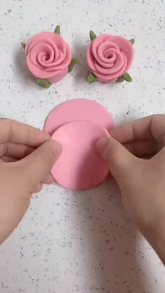 someone is making pink flowers out of fondant on the counter top with their hands