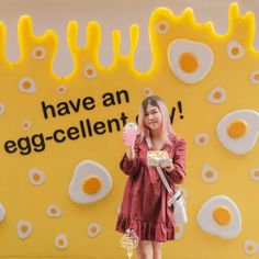 a woman standing in front of a wall with eggs on it