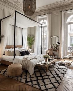 a bedroom with a canopy bed and rugs on the floor, windows in the background