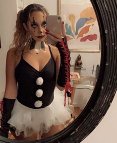 a woman dressed up as a clown taking a selfie in front of a mirror