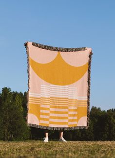 a person standing in front of a large yellow and white blanket on top of a field