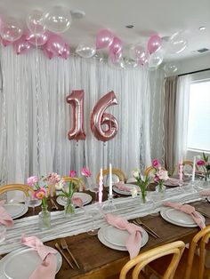 a long table with pink and white balloons on the wall, plates and napkins