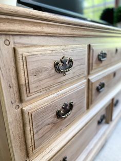 a large wooden dresser with drawers and knobs on it's sides, in front of a flat screen tv