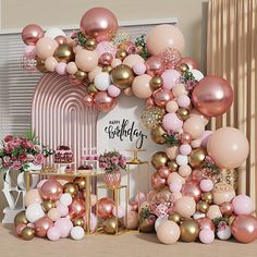 a pink and gold birthday party with balloons on the wall, cake table and decorations