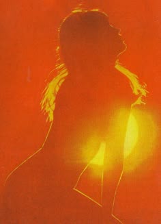 the silhouette of a woman with her hair blowing in the wind, against an orange background