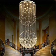 a large chandelier hanging from the ceiling in a room with stairs leading up to it