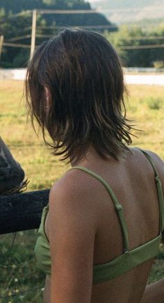 a woman standing in front of a horse looking at it's head through a fence