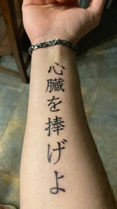 someone is holding up their arm with chinese writing on it