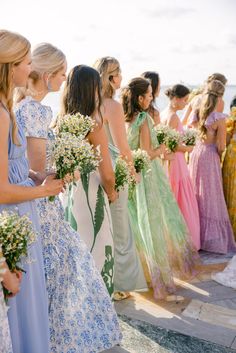 a group of women standing next to each other in dresses and holding bouquets with flowers