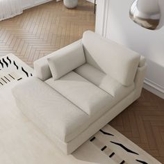 a white couch sitting on top of a hard wood floor next to a lamp and window