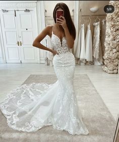 a woman taking a selfie while wearing a wedding dress in a bridal gown shop