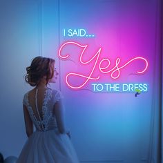 a woman standing in front of a neon sign that says yes to the dress