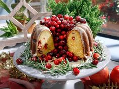 a christmas cake with cranberries and icing on a platter next to other holiday decorations