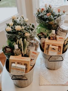 two buckets filled with flowers sitting on top of a table next to each other