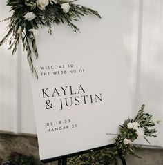 a welcome sign with flowers and greenery on it for a wedding ceremony at the barn