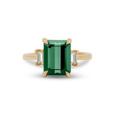 an emerald and diamond ring with two baguets on each side, set in yellow gold