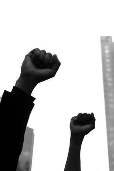 a person raising their fist up in the air with skyscrapers in the back ground