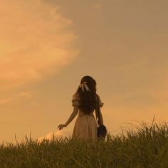 a woman in a white dress walking through tall grass