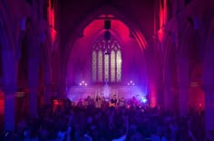 a large group of people standing in front of a building with purple lights on it