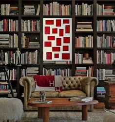 a living room filled with lots of books on top of a book shelf next to a couch