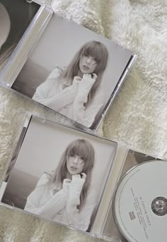 two cd's sitting next to each other on a white blanket with a woman in the middle