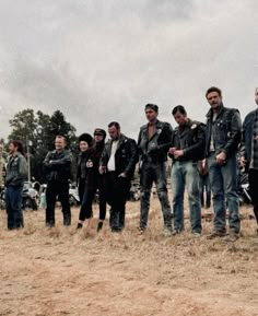 a group of men standing next to each other on top of a dry grass field