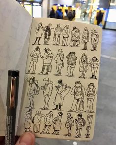 a person holding up a notebook with drawings on it