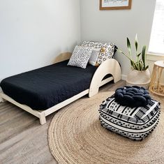 a bed sitting on top of a wooden floor next to a rug and potted plant