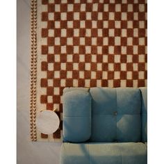 a blue couch sitting in front of a wall with a checkered pattern on it