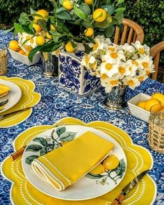 the table is set with yellow and white plates, napkins, and vases