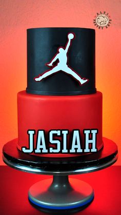 a red and black cake with the word jordan on it's bottom tier is displayed in front of an orange background