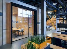 the interior of an office building with wooden tables and chairs, plants in front of glass doors