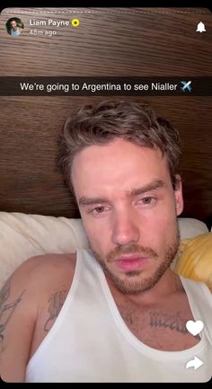 a man in white tank top laying on bed next to banana