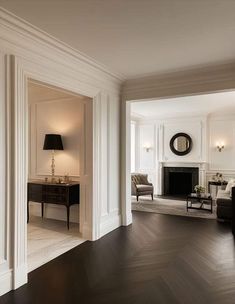 an elegant living room with white walls and wood flooring is seen from the doorway