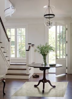 a dining room table with a vase of flowers on it in front of some stairs