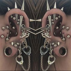 a pair of ear piercings with spikes and chains attached to the sides of their ears