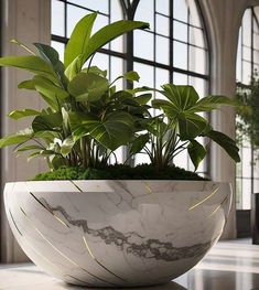 a marble bowl with plants in it sitting on a table next to a large window