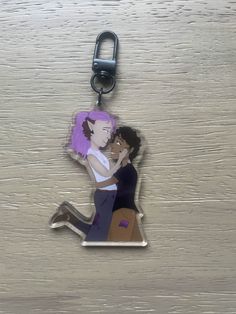 a keychain with an image of two people hugging each other on top of a wooden surface