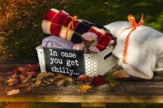 a pile of blankets sitting on top of a wooden bench next to a sign that says i'm case you get chilly