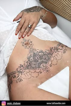 a woman laying on top of a bed next to a white sheet covered in tattoos