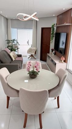 a dining room table with four chairs and a television in the corner, next to a couch