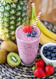 a smoothie in a glass with strawberries, kiwis and blueberries