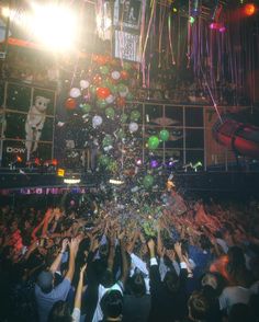 a large group of people are throwing confetti into the air at a party