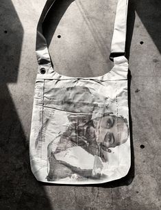 a white bag with an image of a woman's face on it sitting on the ground