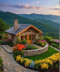 a stone house surrounded by colorful flowers and greenery in the foreground with mountains in the background