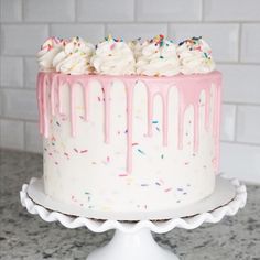 a white cake with pink icing and sprinkles