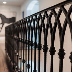 an iron fence in the middle of a room with hardwood floors and white walls on one side